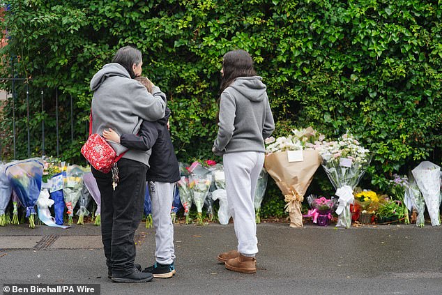 One child died and 21 people were injured when the second coach crashed off a winding stretch of road, flipped onto its roof and slid down a steep bank. Pictured: People lay floral tributes at the scene