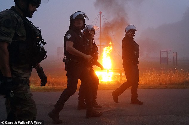 Riot cops are seen near a fire amid clashes with migrants early this morning in France