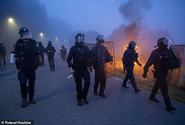 Riot police with shields and tear gas are seen at the scene of the unrest