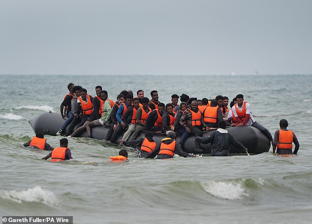 People scramble to board a small boat near Wimereux in France yesterday