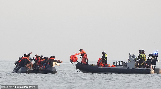 Migrants on board an inflatable boat are handed lifejackets by the French authorities as they leave from Gravelines, France, heading across the Channel to the UK today
