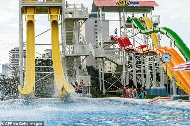 Domestic tourists watch as a man uses a slide into a swimming pool at the Myongsasimni Water Park in the Wonsan Kalma Coastal Tourist Area in Wonsan, North Korea's Kangwon Province on July 2, 2025