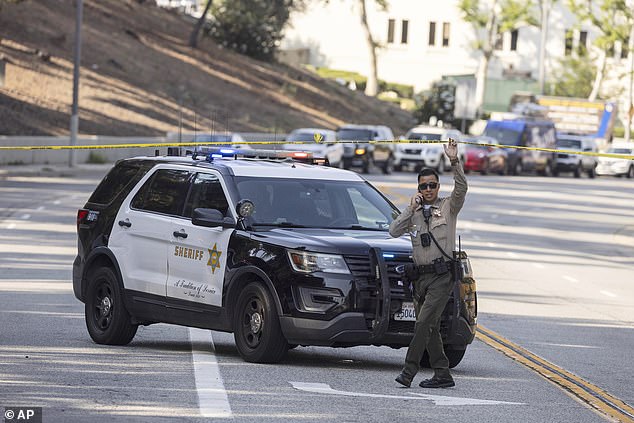 A sheriffs deputy monitors a street closure near the site of an explosion at the L.A. County Sheriff's Special Operations Bureau on Friday