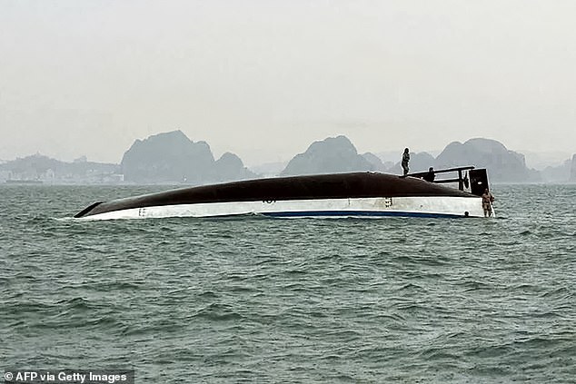 A man stands on a tourist boat that capsized in Ha Long Bay