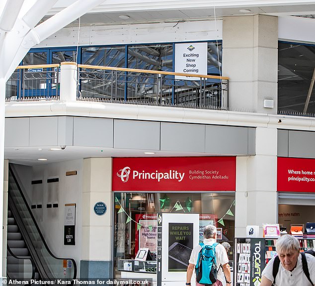 A sign in the shopping centre reads 'Exciting new shop coming soon' but the units upstairs have been empty for some time with shops around them also closing their doors