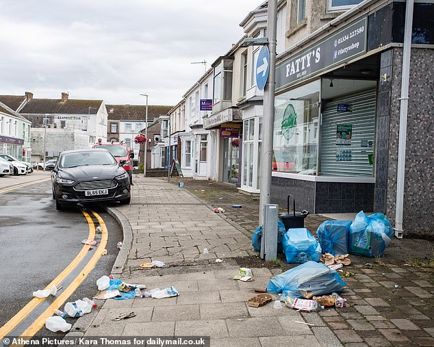 One of the side streets off Llanelli town centre showing closed shops and pavements littered with rubbish