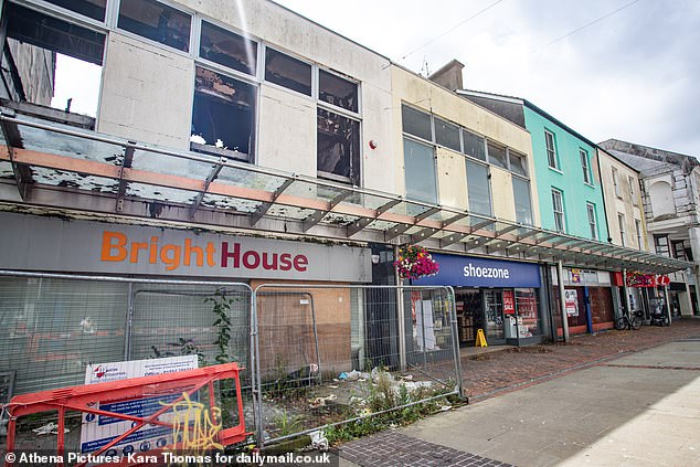 Along the high street are empty shops, vandalised and burnt down, next to chains advertising sales