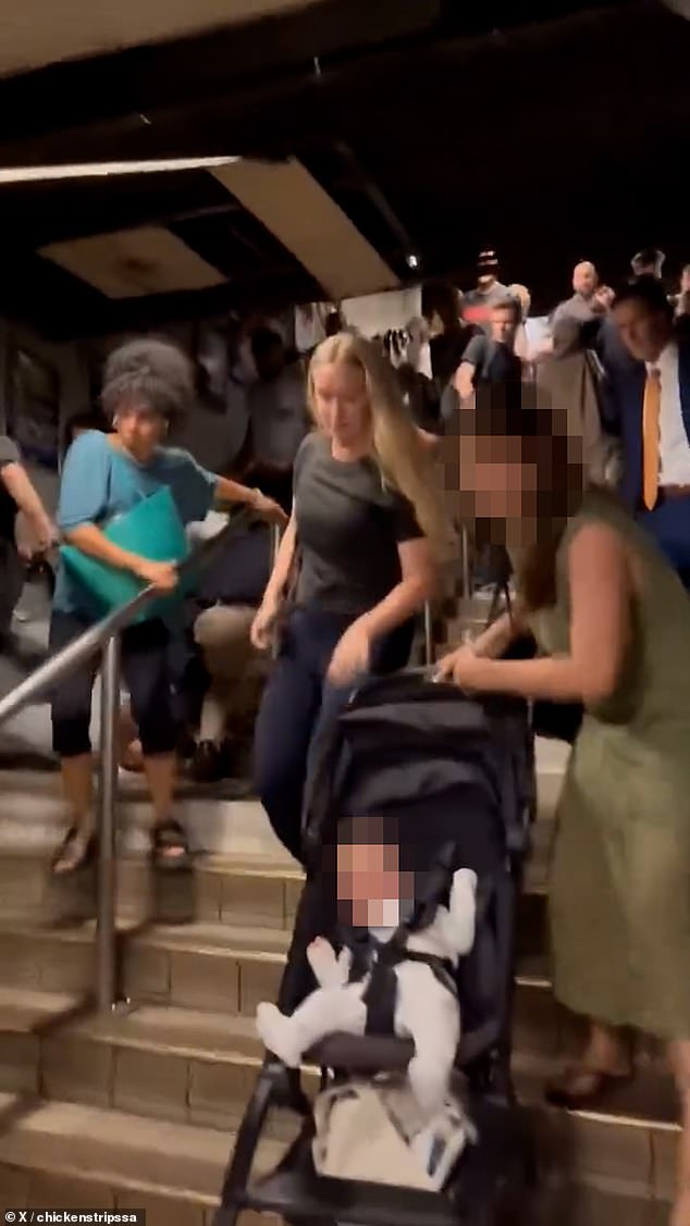 The mother of the toddler crying on the ground was seen rushing to the boy's aid, without noticing the pram she had been holding onto had began to roll down an incline