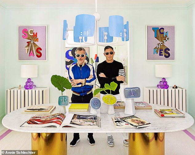 Jonathan (right) and Simon in the dining room. The words on the artworks behind them are Yiddish for clothing and decorative items – fields that the couple are known for.