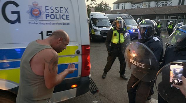 The injured man then looks down at his hand in disbelief as he clasps his teeth and shows them eagerly to fellow protesters