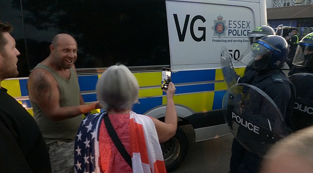 The injured man shows his teeth eagerly to fellow protesters including a lady with the Flag of St. George draped over her shoulders