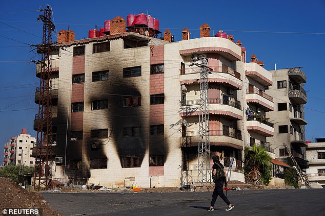 A bedouin fighter walks near a burnt building after sectarian clashes escalated on July 19