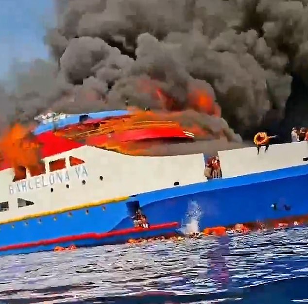 A number of passengers in orange life vests are forced to enter the sea as they sit on the edge of the vessel