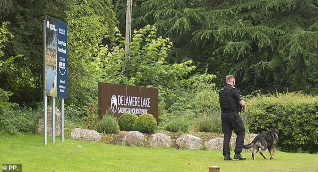 A police officer with a dog is seen searching Delamere Lake Sailing & Holiday Park
