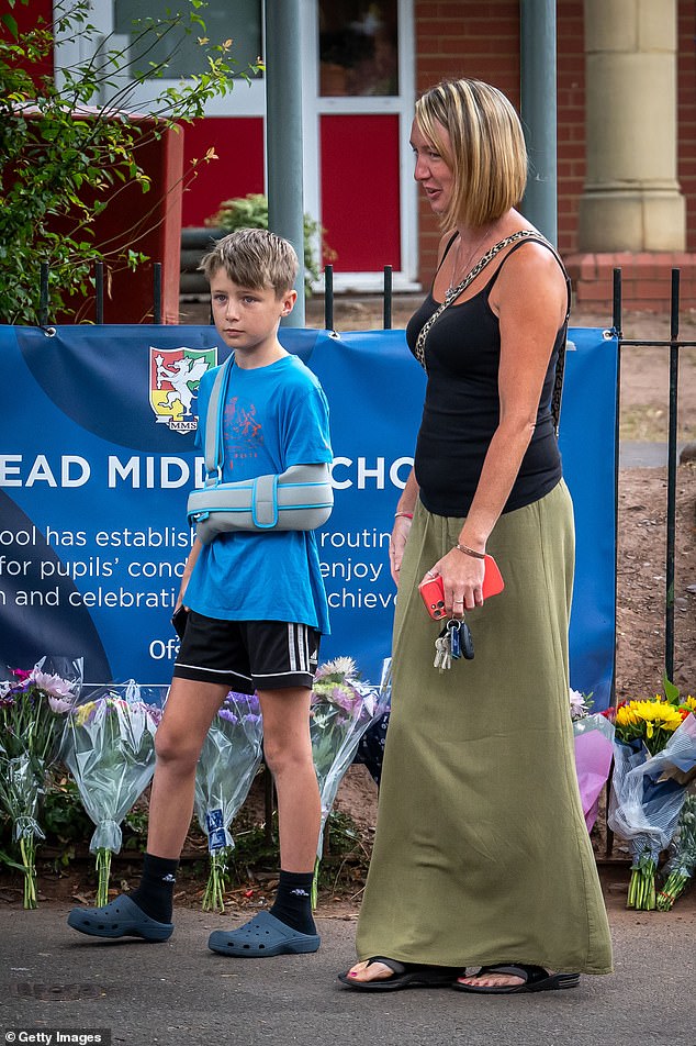 Jayden, who was a passenger on the bus and was treated for a suspected broken collarbone, with his mother outside Minehead Middle School