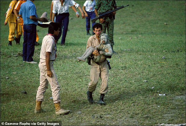 A volunteer carries a child covered in mud after the eruption of Nevado del Ruiz in 1985