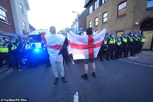 People wrapped in St George's flag faced down riot police who lined up in a queue on Hemnall Street