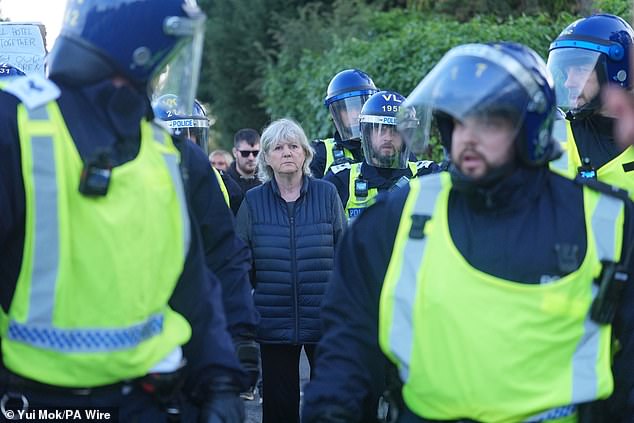 Police surrounded a woman, who was escorted by police out of the area as a group of masked protesters followed her and shouted abuse