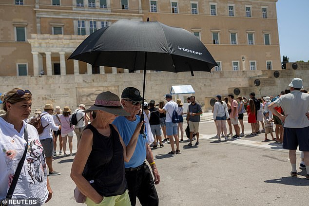 A person holds an umbrella in front of the parliament building during a heatwave in Athens, Greece, July 22, 2025