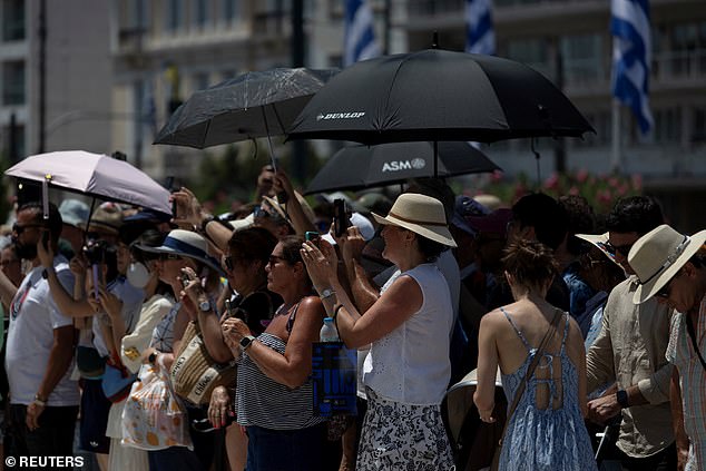 People hold umbrellas as they watch Greek Presidential Guards perform during a change of the guard at the Tomb of the Unknown Soldier, in front of the parliament building during a heatwave, in Athens, Greece, July 22, 2025