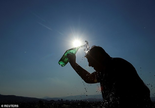 Victor, a tourist guide, pours water from a bottle to cool off during hot weather in Skopje, North Macedonia, July 21, 2025