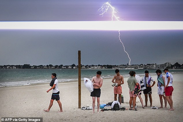 FRANCE: A lighting bolt lights up the sky as people prepare to leave the beach during a thunder storm over the city of La Baule