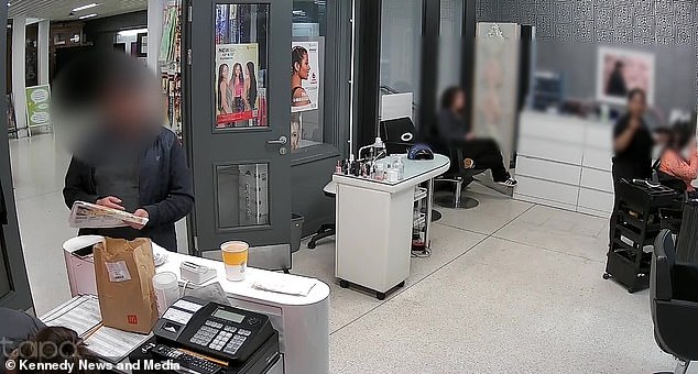 Footage shows the cap-wearing thief take the chance to unfold his newspaper and place it over her Samsung phone that was sitting on top of the desk