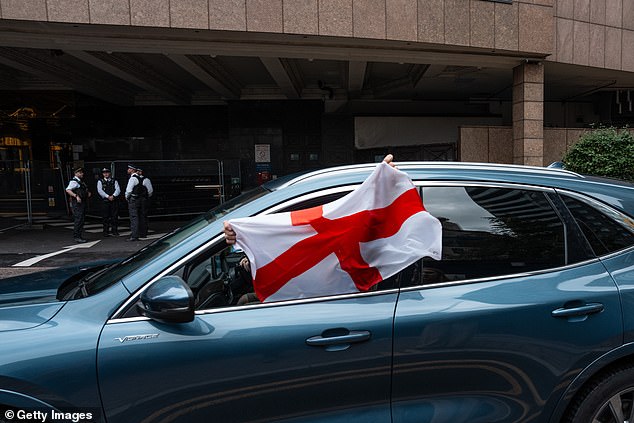 A person waves an English flag from a car as it passes the Britannia International Hotel in Canary Wharf