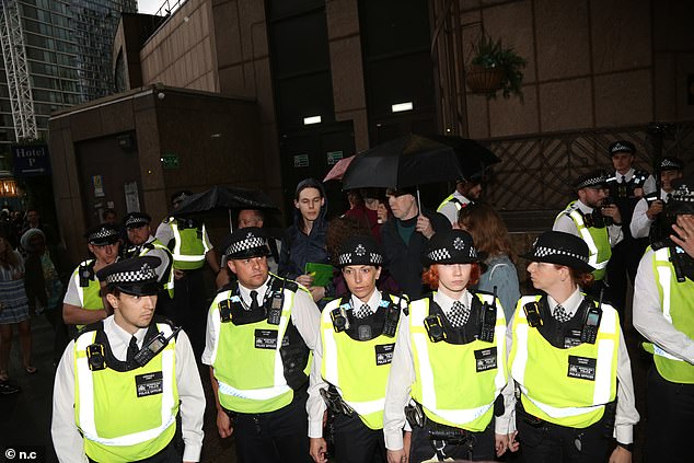 Police officers gather in front of counter-protesters outside the Canary Wharf hotel