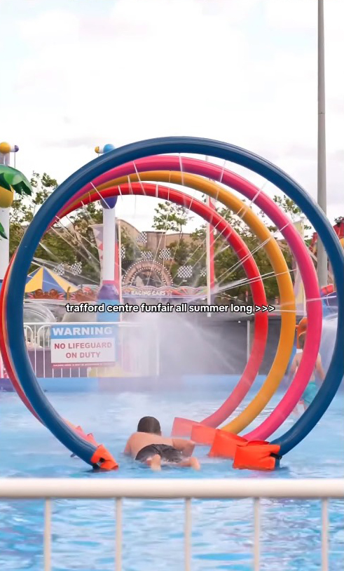 Person swimming under colorful arches at a summer funfair.