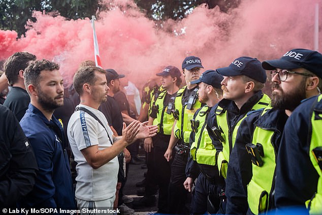Anti-immigration protesters confront a cordon of riot police officers preventing them from getting near a small group of counter-protesters in Epping on July 17