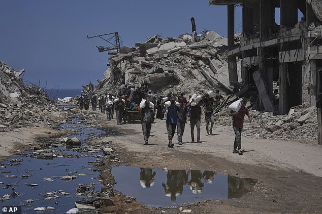 Palestinians carry sacks of flour unloaded from a humanitarian aid convoy in Gaza today