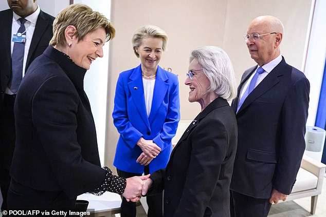 Swiss Federal President Karin Keller-Sutter (L) shakes hands with Founder and executive chairman of the Board of Trustees of the WEF Klaus Schwab (R) and his spouse Hilde Schwab (2R) next to European Commission President Ursula von der Leyen