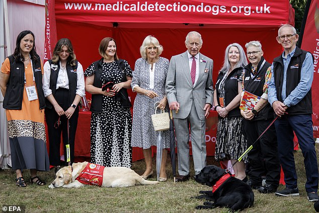 Britain's King Charles III (C-R) and Britain's Queen Camilla (C-L) pose for a picture as they meet Medical Detection Dogs staff and dogs