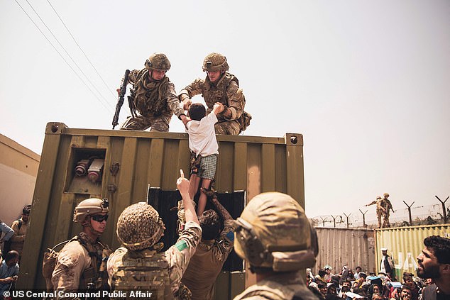 British, Turkish and US military help a child during the evacuation of Kabul in 2021