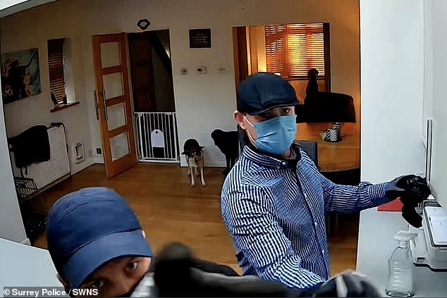 A separate video sees a man in a blue cap, black balaclava and gloves inside a property grabbing belongings while holding a spray bottle of liquid, before being joined by another man