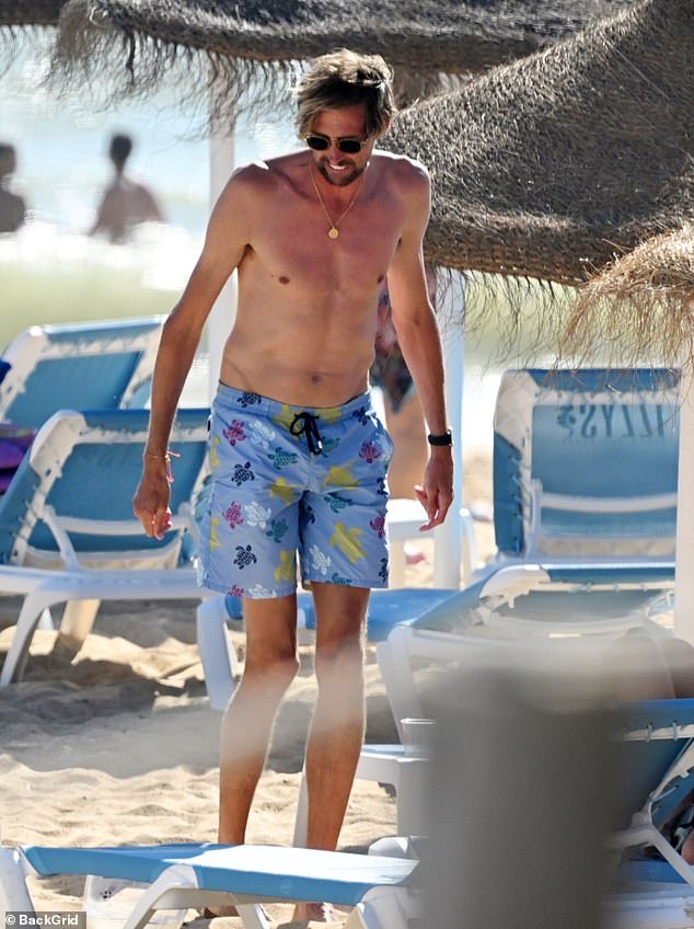 Former footballer Peter showed off his muscular frame as he went shirtless in a pair of blue board shorts with turtles printed across them
