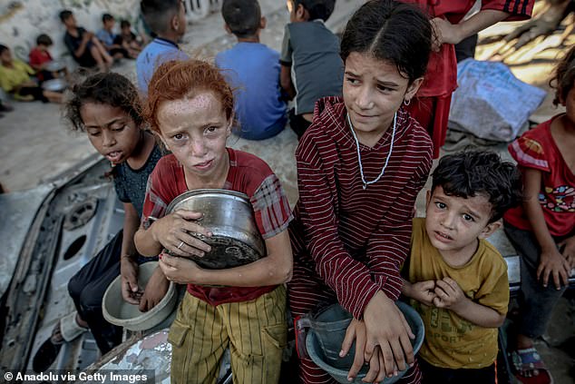 Palestinians carrying pans, gather to receive hot meals, distributed by a charity organization in Gaza City, where residents are struggling to access food due to the ongoing Israeli blockade and attacks in Gaza City, Gaza on July 23, 2025