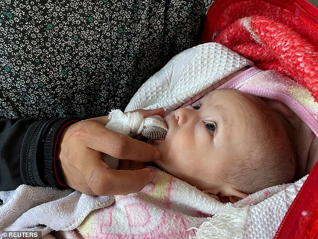 Palestinian woman Warda Mattar feeds her newborn dates, instead of milk, amidst food scarcity and lack of milk, at a school where they shelter in Nuseirat in the central Gaza Strip February 25, 2024