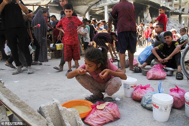 A child eats as Palestinians gather to receive food cooked by a charity kitchen, amid Israel-Hamas conflict, near the ruins of houses destroyed during the Israeli offensive, in Jabalia in the northern Gaza Strip August 26, 2024
