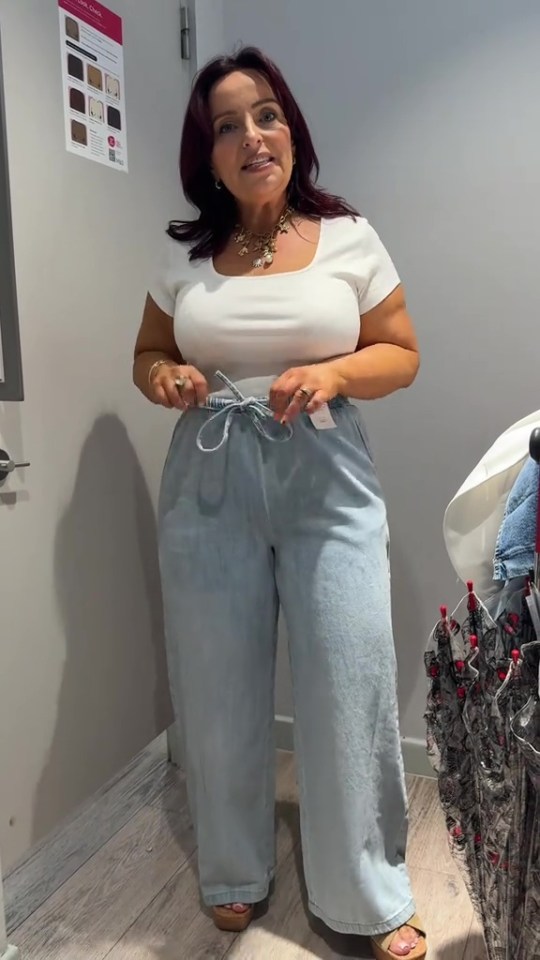 Woman trying on light blue jeans.