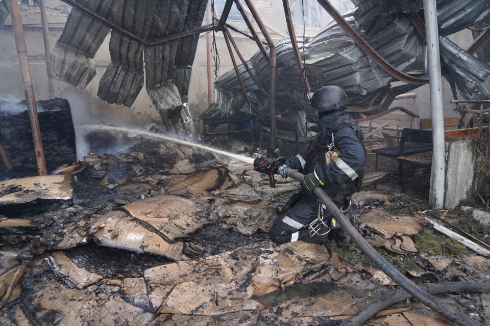 Firefighter extinguishing a blaze in a damaged building.