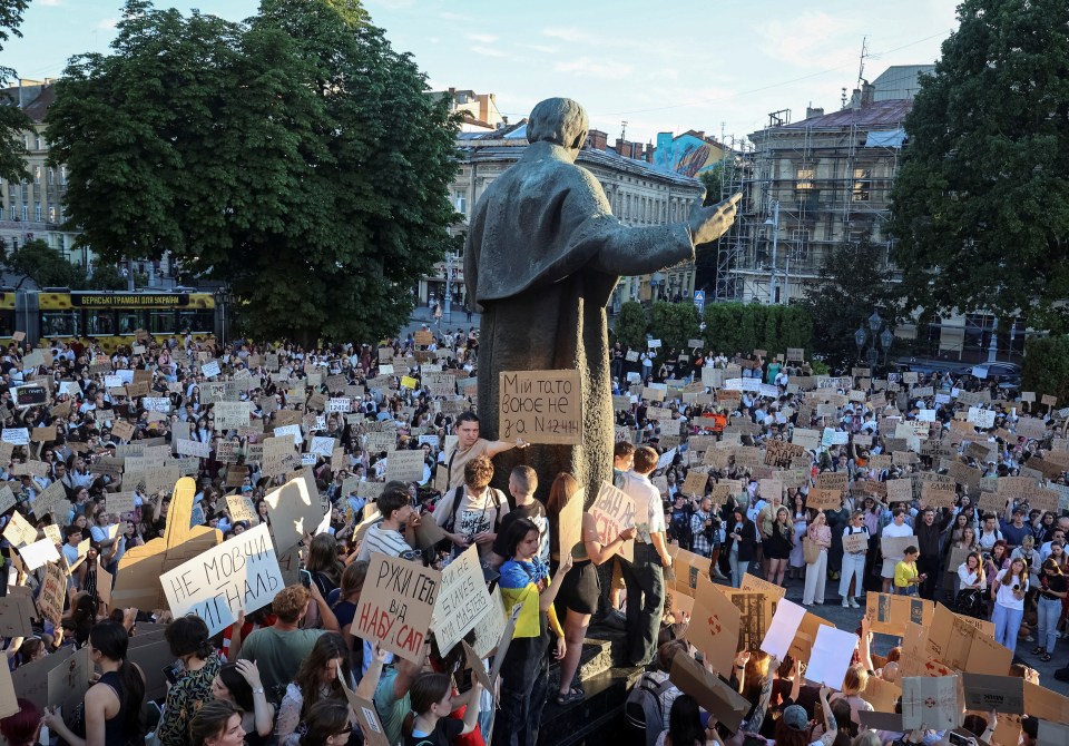 Protesters in Lviv, Ukraine, holding signs at a wartime rally against a law curbing anti-corruption institutions.
