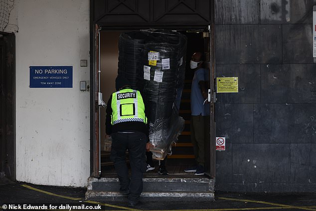 Security carry a large package behind the cordon and into the Canary Wharf hotel today