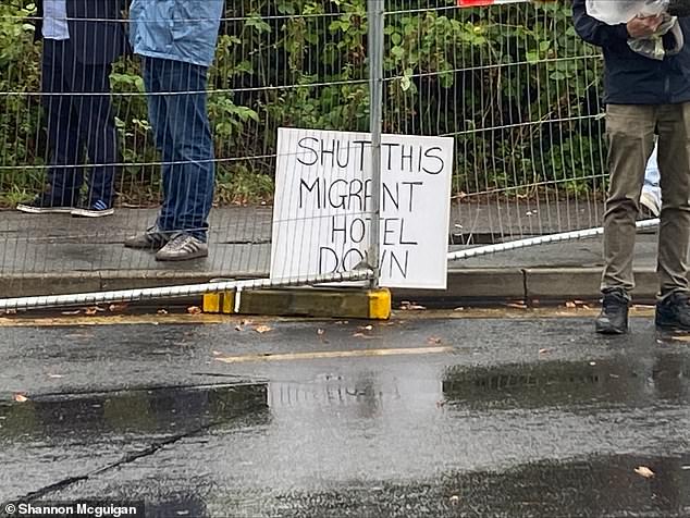 Another sign tied to the metal barriers surrounding the perimeters of the hotel reads 'Shut this migrant hotel down'