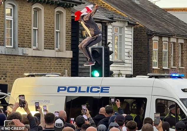 A protestors jumps up and down on the roof of a police van at a protest on July 17 outside The Bell Hotel