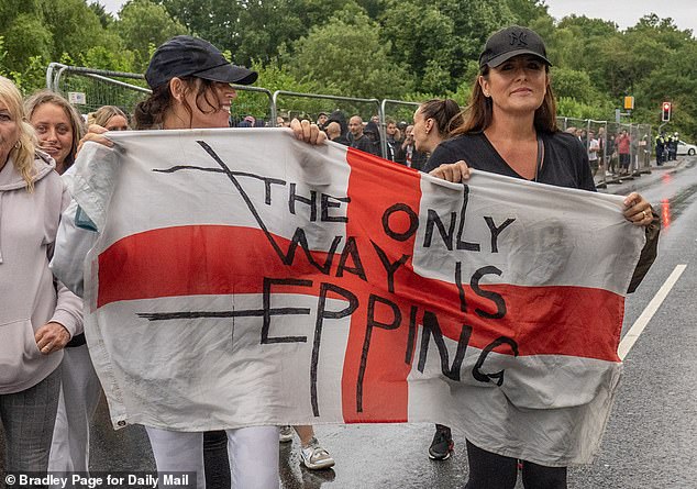 Protesters march in the streets of Epping last night, with two women carrying an English flag bearing the slogan 'The Only Way is Epping'