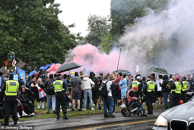 A number of protesters braved the rain as people release flares in Union Jack colours while police watch on - though the turnout was smaller than the event on July 17 that spilled over into rioting