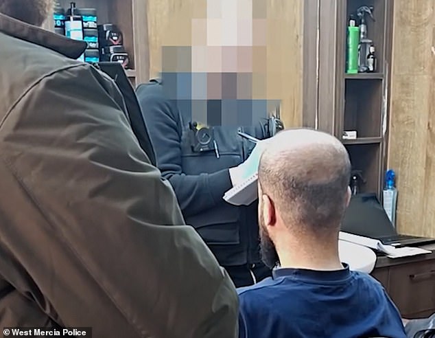 A West Mercia Police officer speaks to a man inside one of the Turkish barbers raided earlier this year as part of Operation Machinize