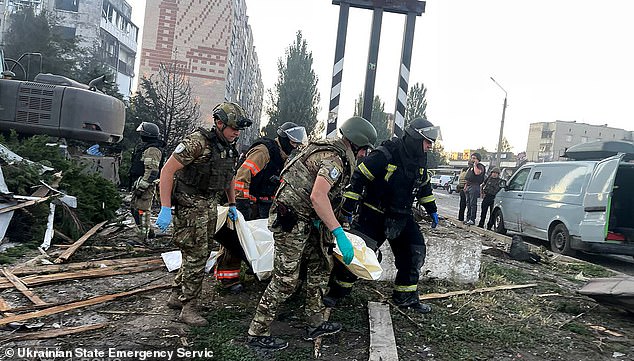 Rescuers carry a body from a damaged civilian installation following a Russian strike in Dobropillia, Donetsk region, July 16, 2025